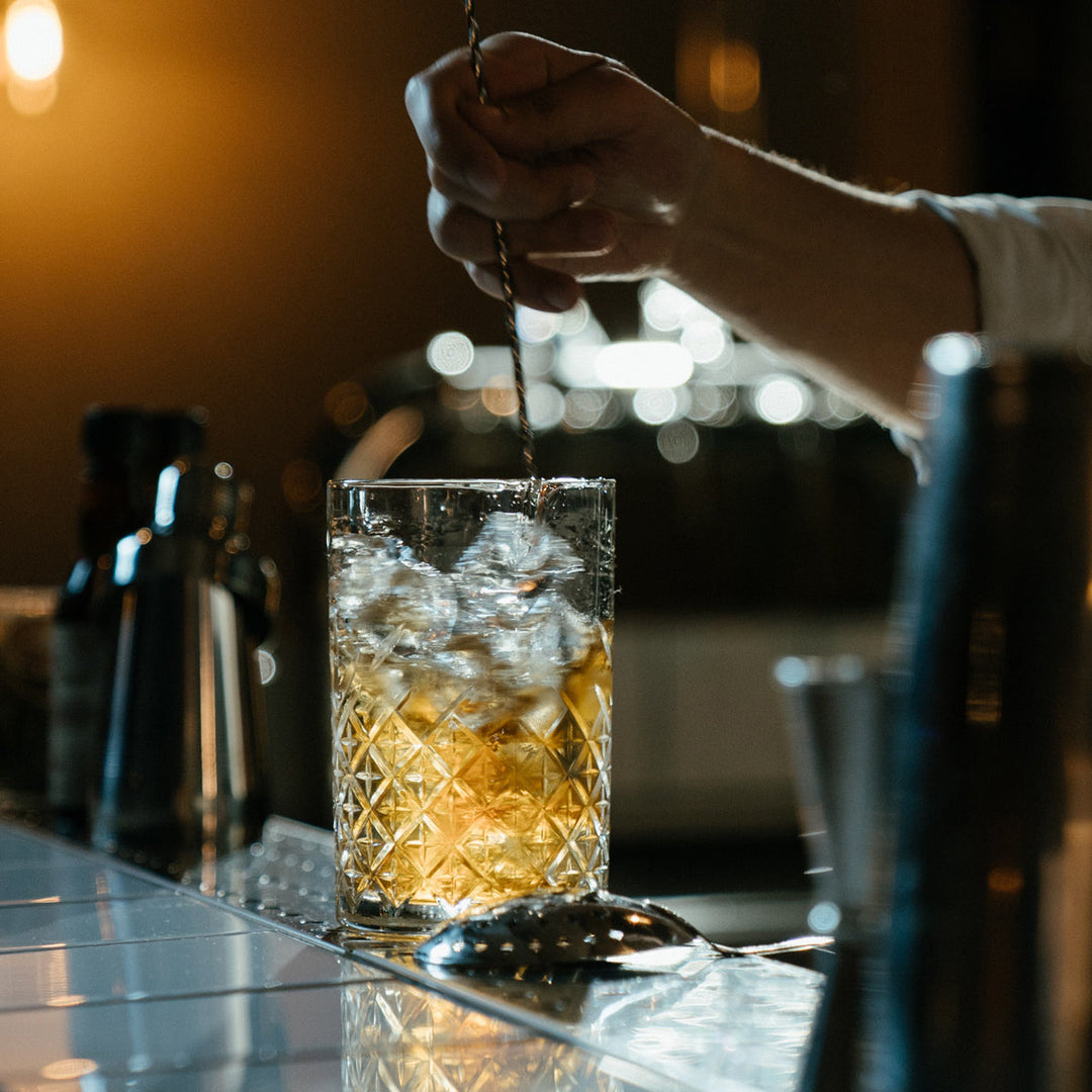Bartender som rör om en drink i det mönstrade blandningsglaset