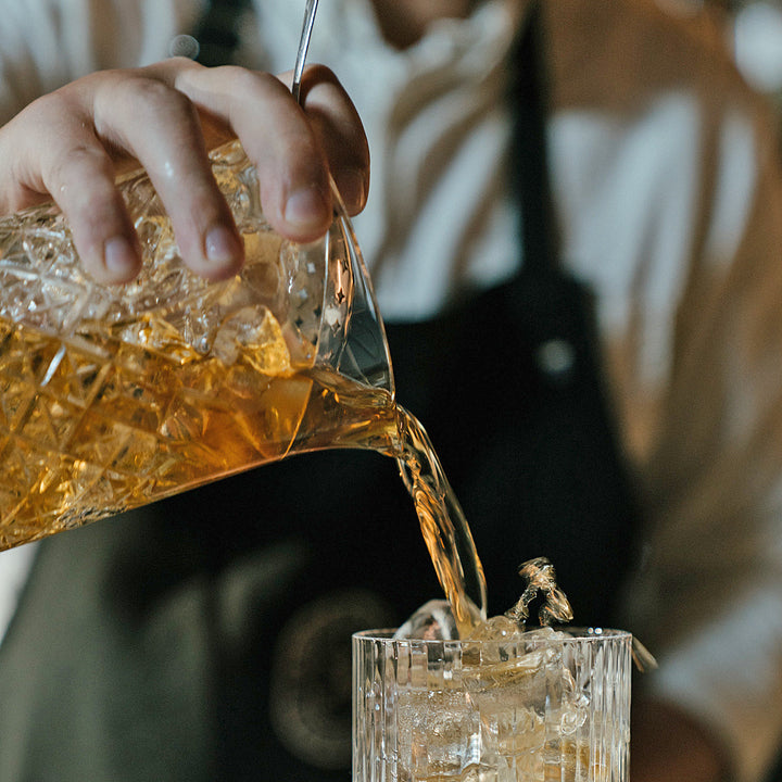 Hällning av färdig cocktail från det eleganta blandningsglaset
