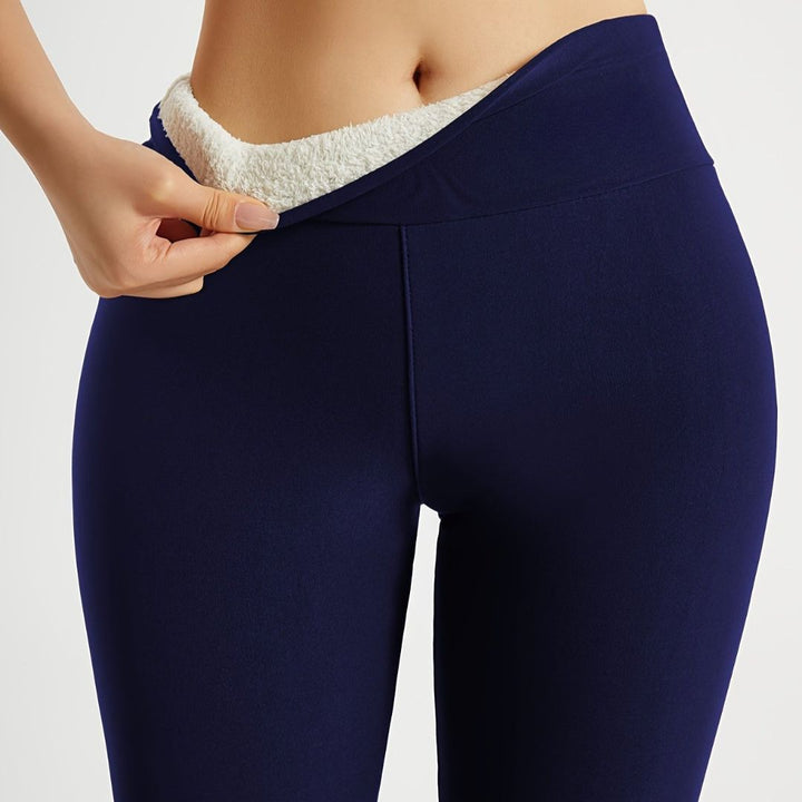 Modell som bär svarta termoleggings under aktivitet i snö.