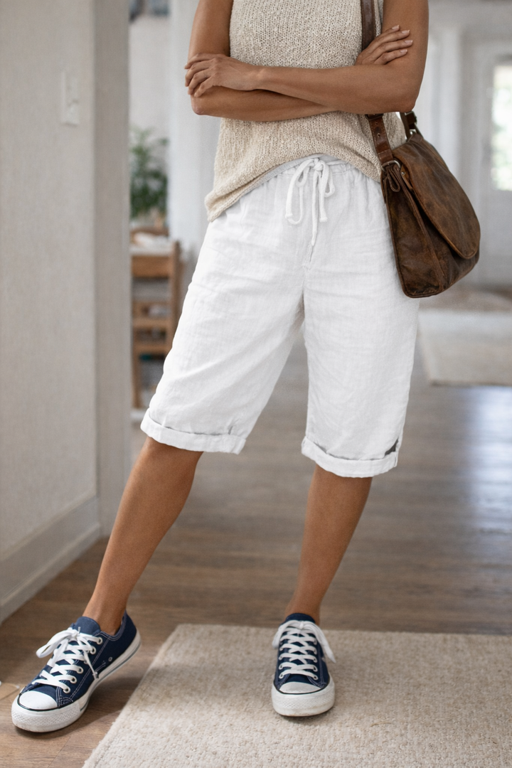 Kvinna i vita bermudashorts med dragsko och blå sneakers