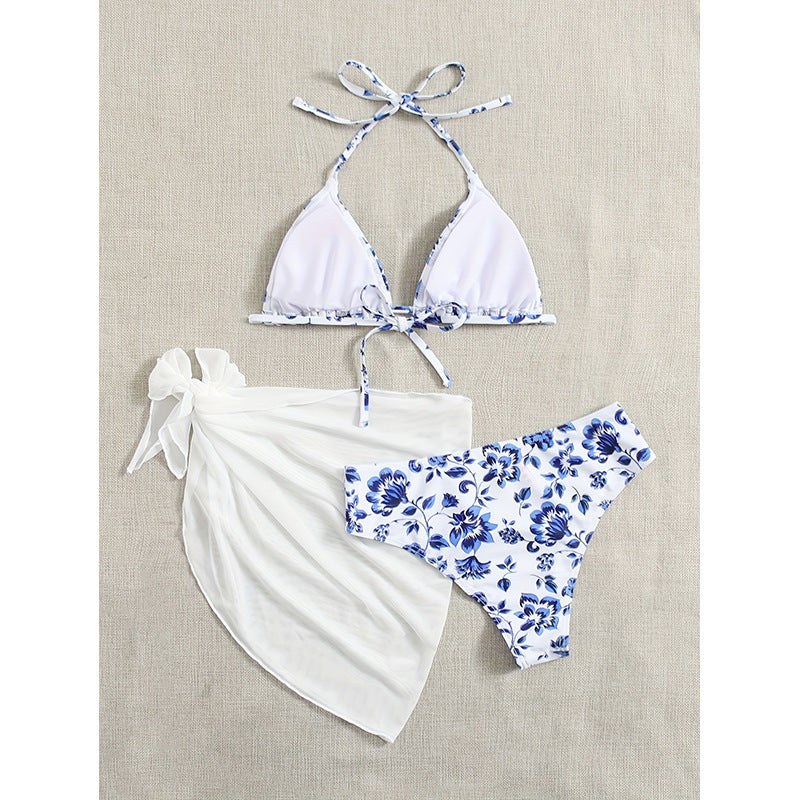 Modell i dam triangelbikini med blommigt mönster & sarong. Stilfulla badkläder & strandmode, perfekt för semestern.