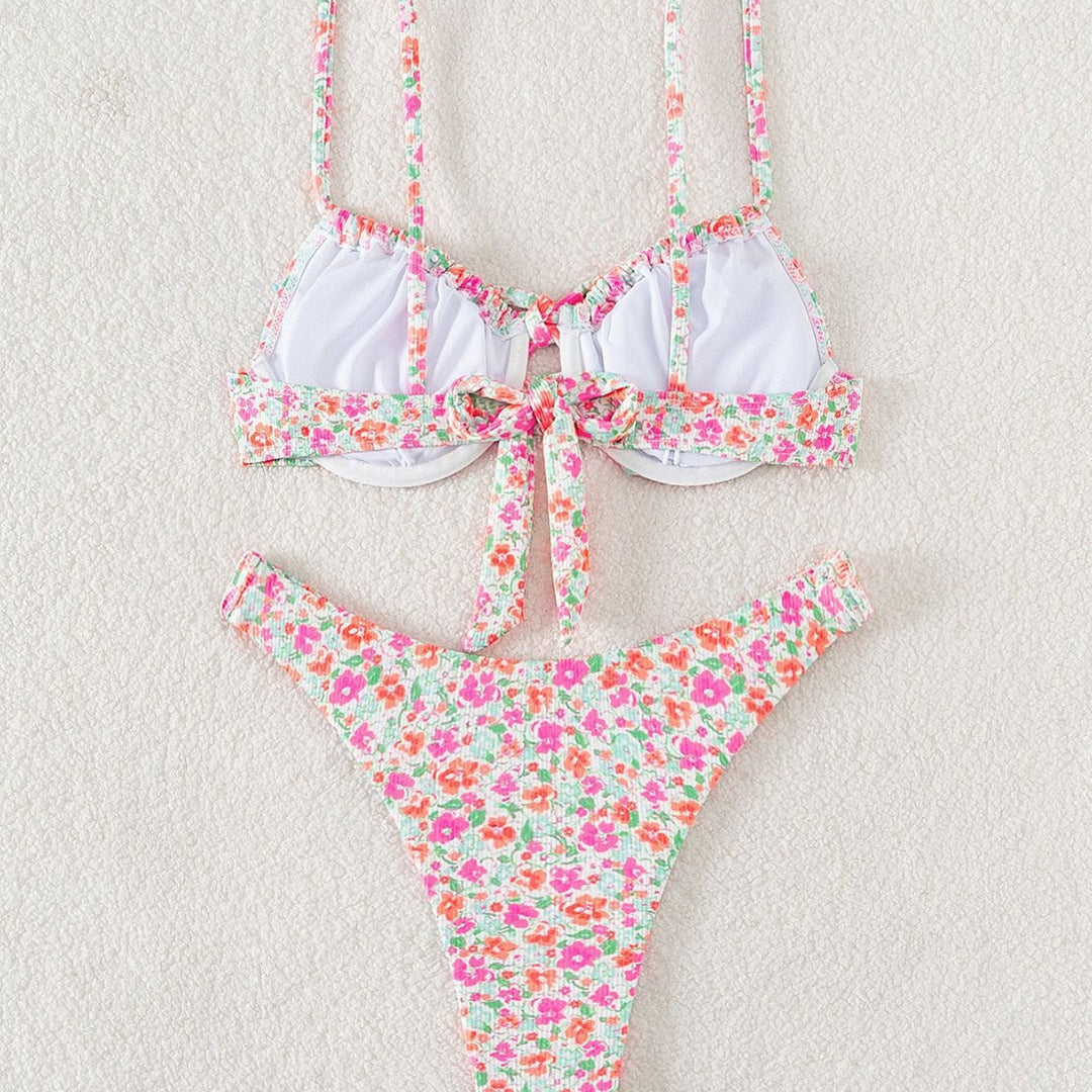 Modell bär dam triangelbikini med blommönster och justerbara axelband på en solig strand. Badkläder.