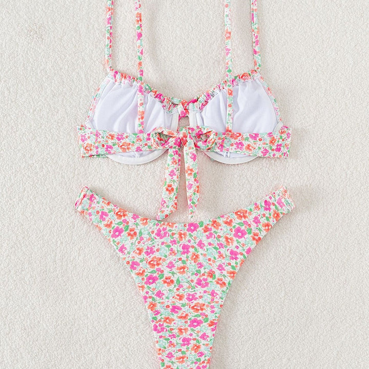 Modell bär dam triangelbikini med blommönster och justerbara axelband på en solig strand. Badkläder.