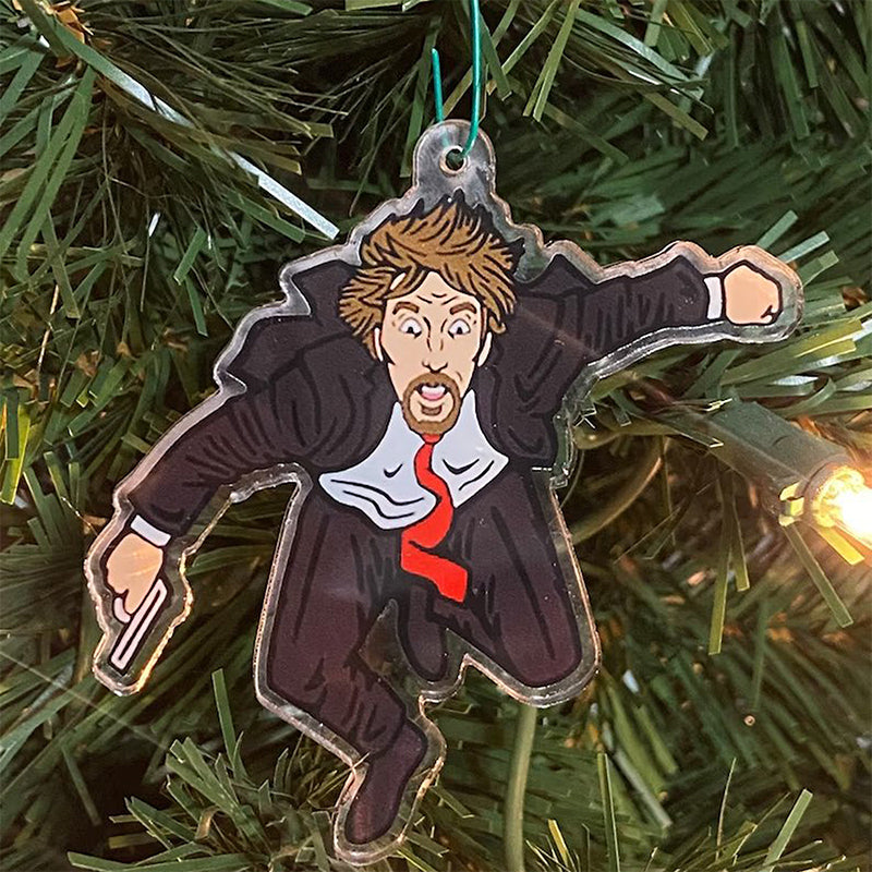 "Detaljerad trä Adventskalender med Die Hard-motiv, visar Hans Gruber faller från brunblå Nakatomi Plaza, roterbar design."
