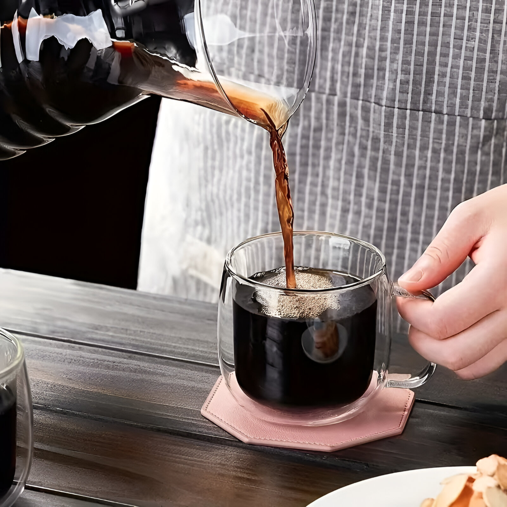 Elegant dubbelväggig kaffekopp med ångande varmt kaffe, tillverkad av klart borosilikatglas.