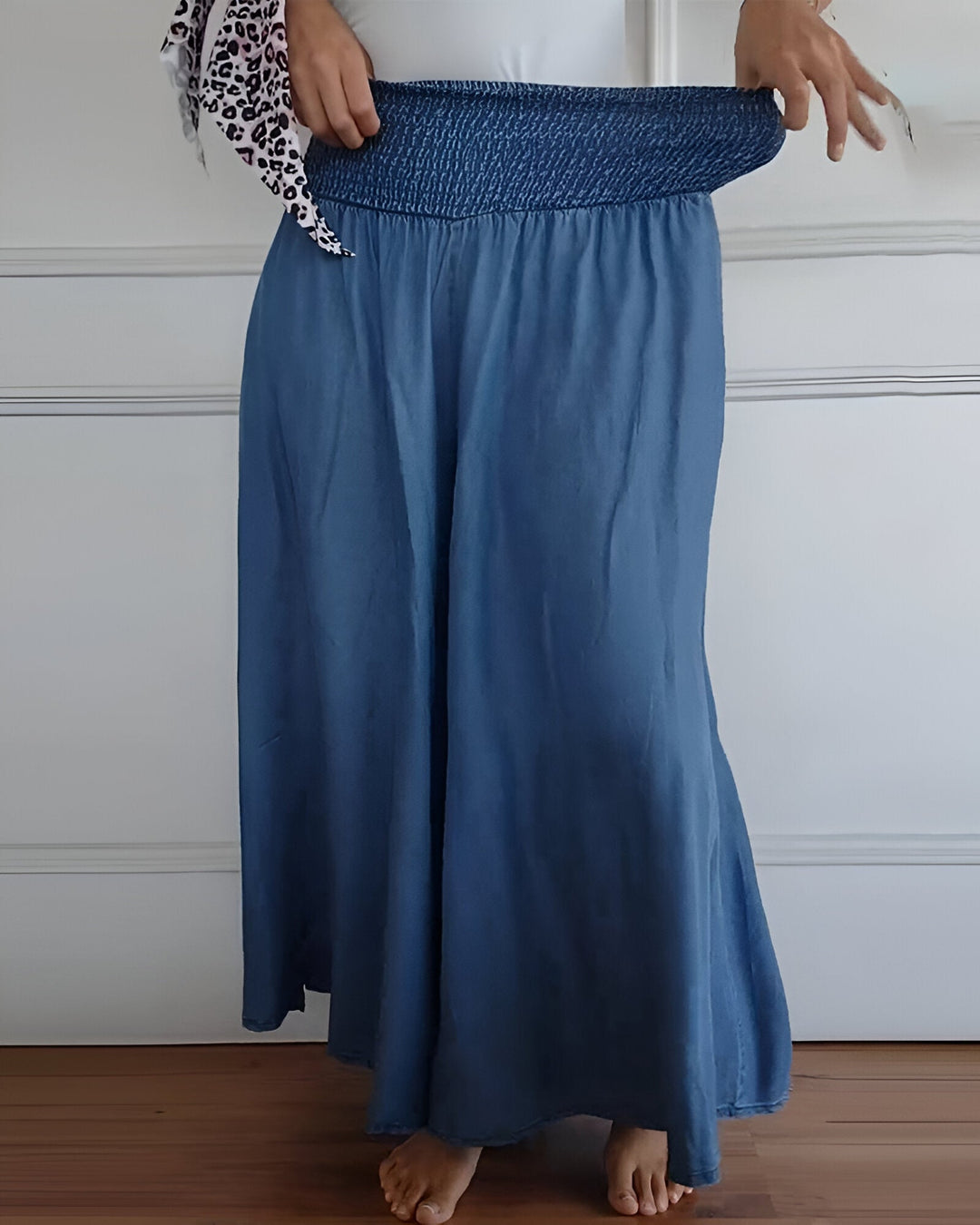 Närbild på smockad midja och vida byxben i blått