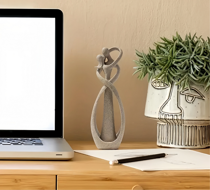 Abstrakt staty placerad på ett skrivbord bredvid en bärbar dator