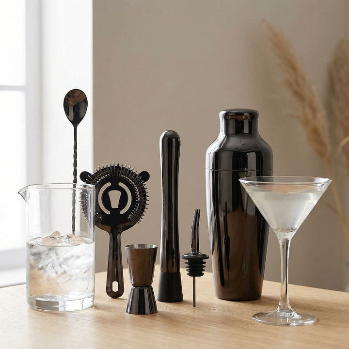 Komplett silverfärgat barset med shaker, jigger och drinkverktyg i rostfritt stål, på bambustativ.