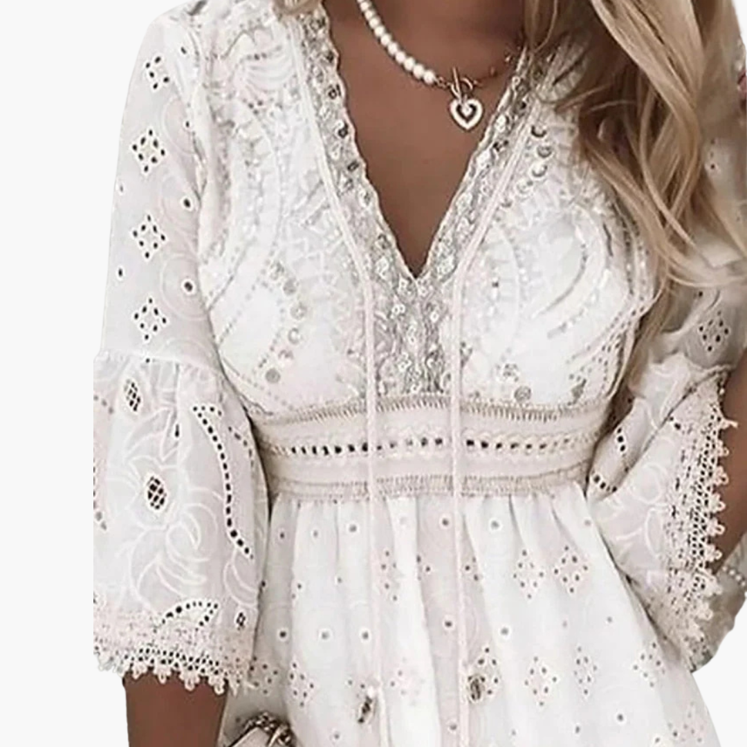 Vit elegant damklänning med V-ringning, utsvängda ärmar och broderade detaljer för sommar och fest.