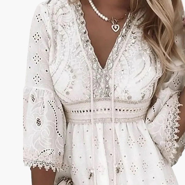 Vit elegant damklänning med V-ringning, utsvängda ärmar och broderade detaljer för sommar och fest.