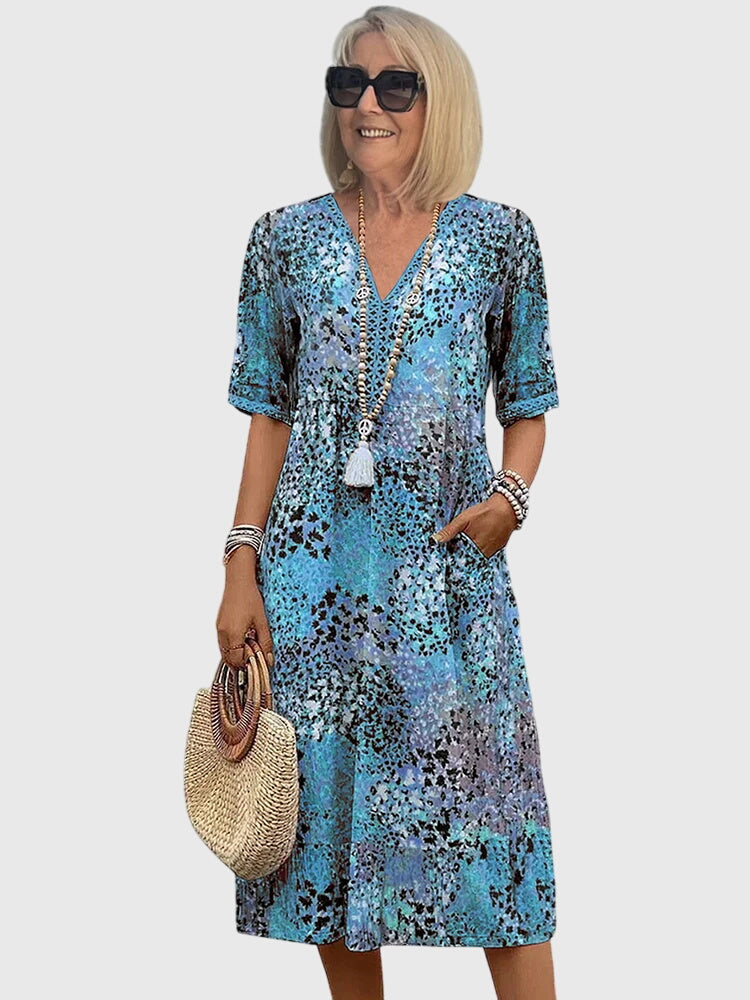 Blommig midi damklänning med flödande snitt. Trendig sommarklänning för dammode.