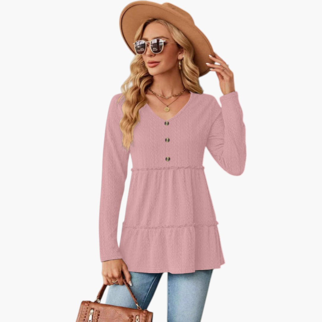 Rosa damtop med långa ärmar. Elegant V-ringning och dekorativa knappdetaljer ger en sofistikerad look.