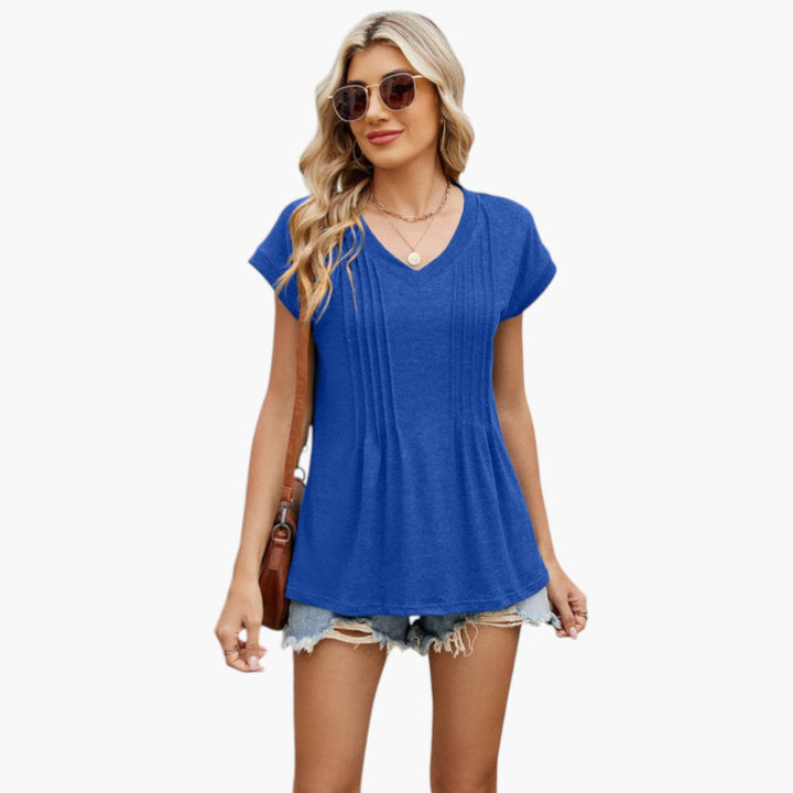 Närbild på den eleganta V-ringningen och veckade fronten på dam-t-shirten. Stilren sommar topp.