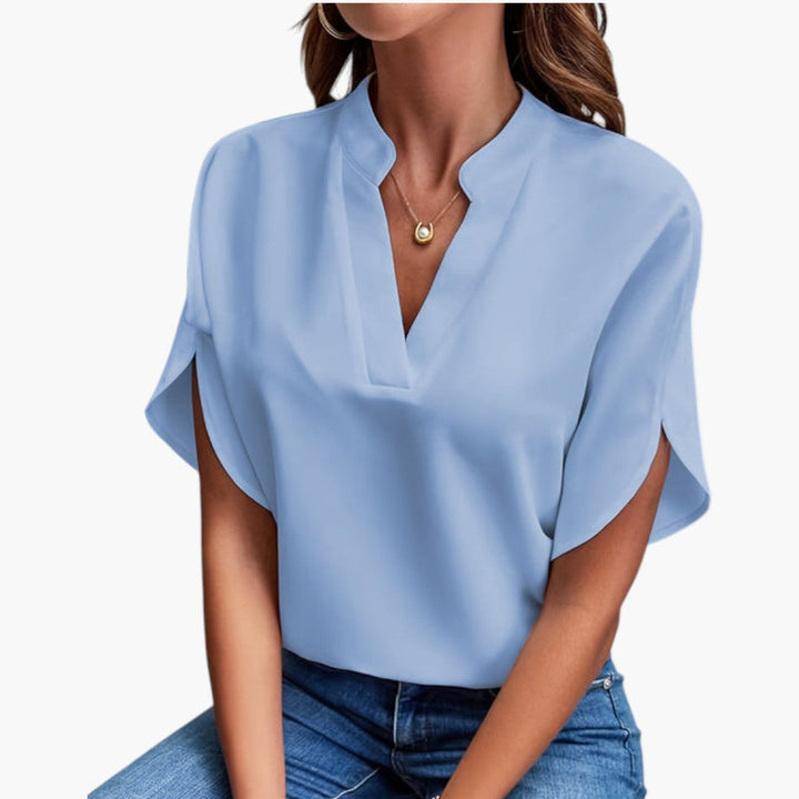 Stilfull damblus med V-ringning, korta ärmar och elegant design för modern damgarderob.