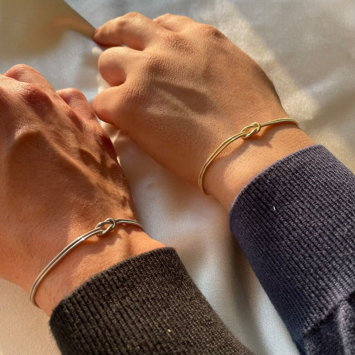 Handled med guldarmband och silverarmband bredvid varandra