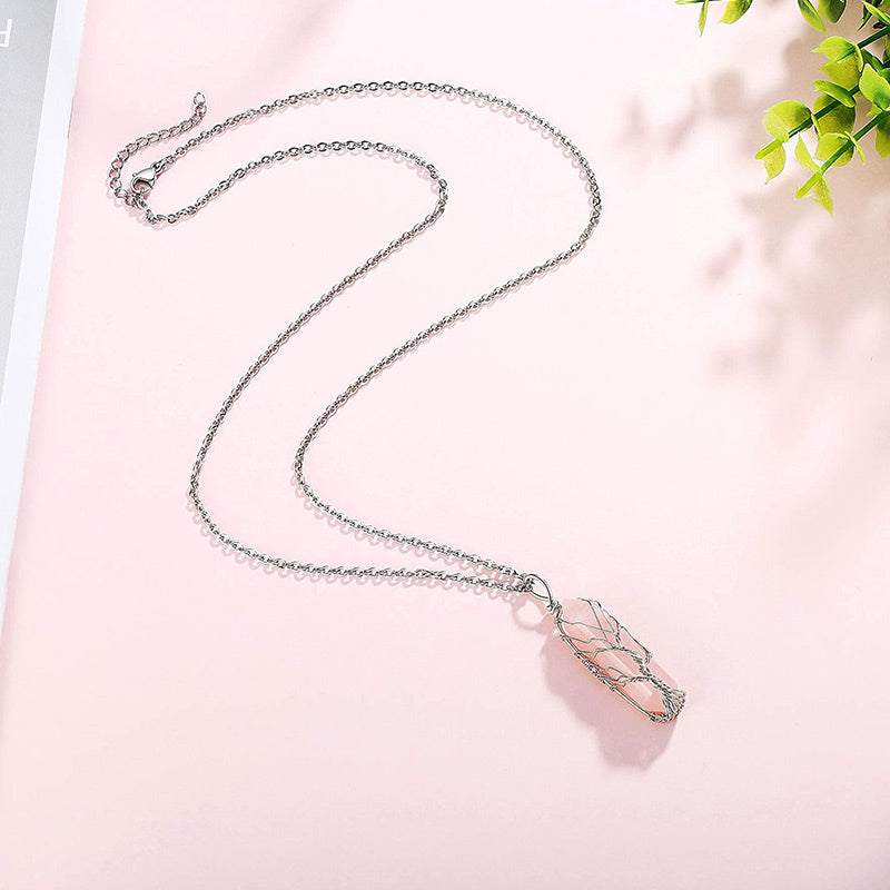 Närbild på silverhalsband med Livets Träd-motiv och en skimrande kristall.
