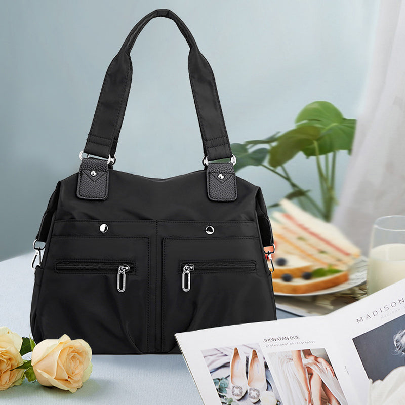 "Elegant damryggsäck i vattenavstötande nylon, flera fickor, svart, perfekt för arbete och resor."