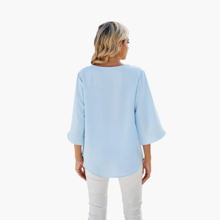 Närbild på ledig kvinnoblus med trekvartsärmar och eleganta sprunddetaljer, framhäver feminin design.