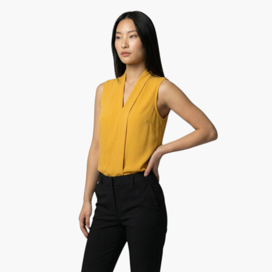 Vit ärmlös blus för dam med stilren V-ringning & elegant veckad front. Bekväm för sommarvardag & fest.