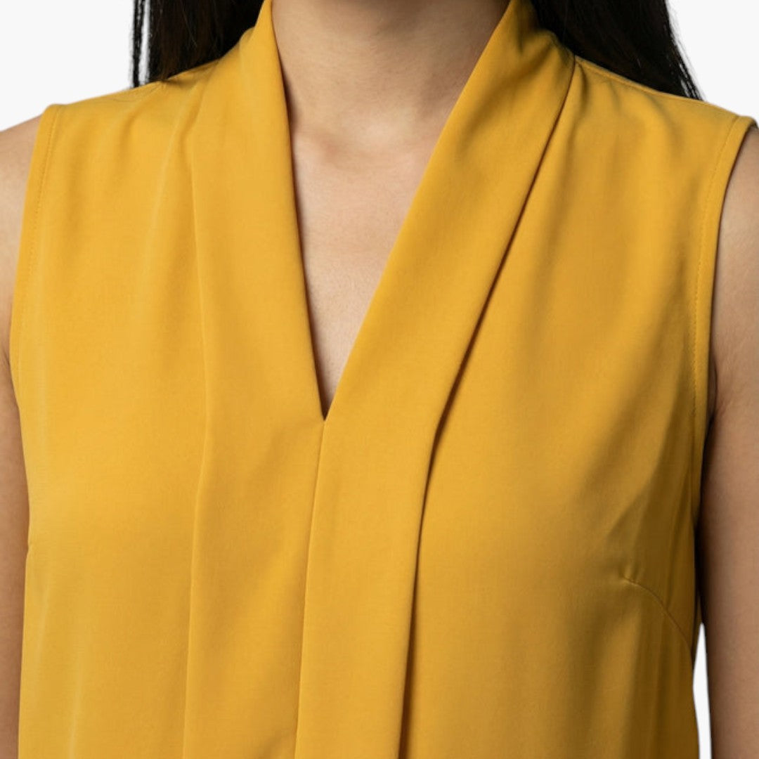 Bekväm beige damtopp, ärmlös med smickrande V-ringning & detaljerad veckad front. Idealisk för sommar.