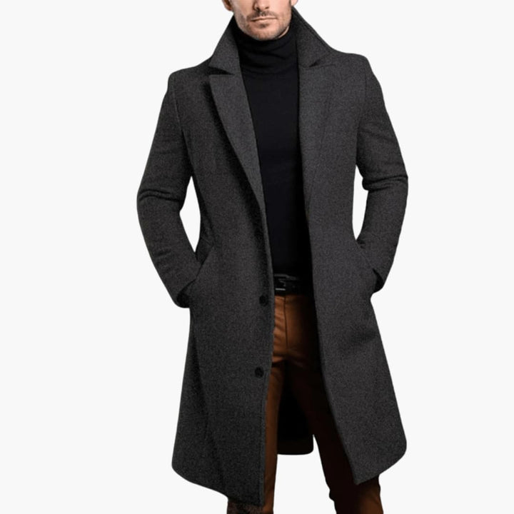 Närbild på klassisk lång kappa för män, visar slagkrage, knappar och tygets varma kvalitet. Formellt ytterplagg.
