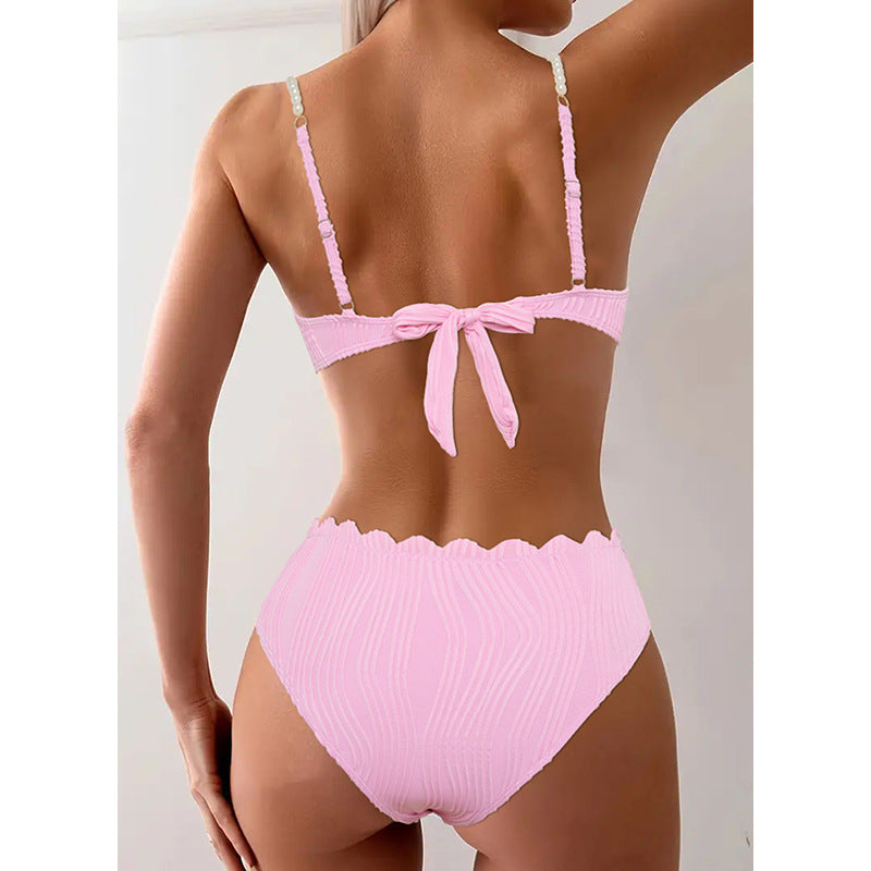 Detaljbild på rynkad rosa bikiniöverdel med push-up funktion som framhäver silhuetten.