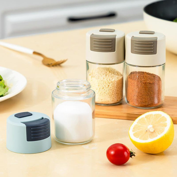 Elegant saltkärl i glas med mätfunktion, böjd form och modernt lock, perfekt för kryddförvaring i köket.