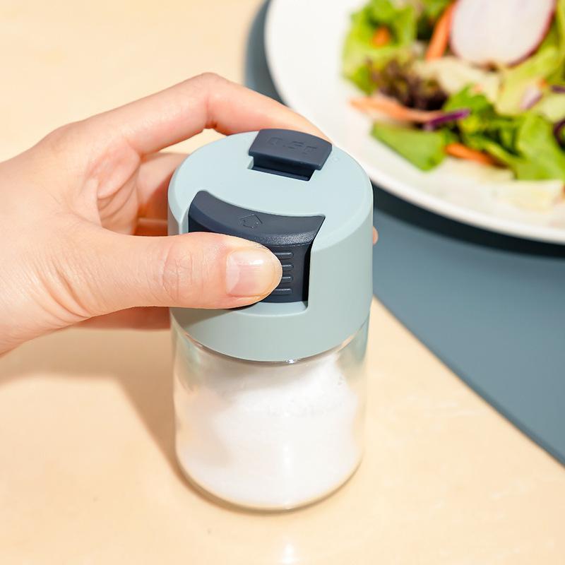 Elegant saltkärl i glas med mätfunktion, böjd form och modernt lock, perfekt för kryddförvaring i köket.