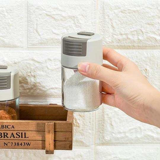 Elegant saltkärl i glas med mätfunktion, böjd form och modernt lock, perfekt för kryddförvaring i köket.