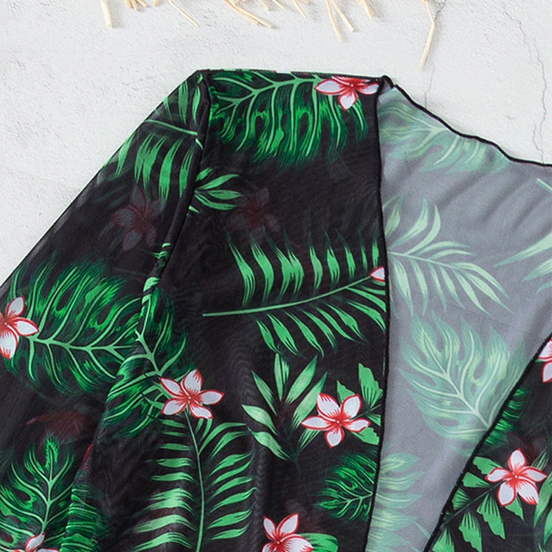 Dam-strandset i svart med blommig kimono och bikini. Trendig badmode för en stilfull sommarsemester.