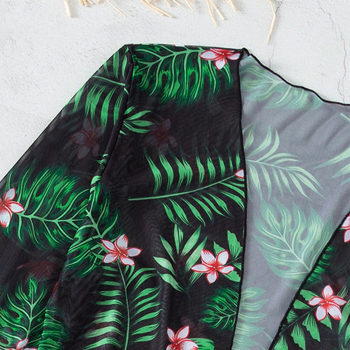 Dam-strandset i svart med blommig kimono och bikini. Trendig badmode för en stilfull sommarsemester.