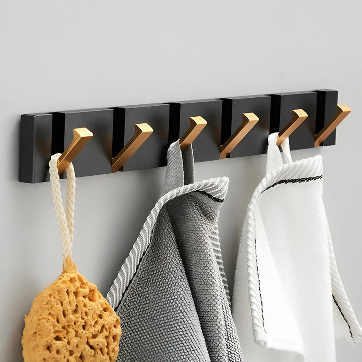 Robust väggkroklist i svart med guldfinish, designad för både funktion och skönhet i hemmet.