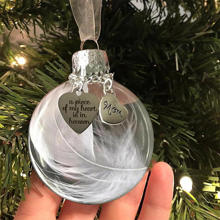 Elegant transparent julkula med vit fjäder och gravering, perfekt för juldekoration eller som en omtänksam gåva.