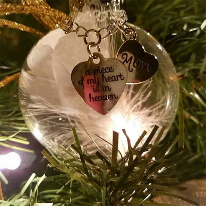 Elegant transparent julkula med vit fjäder och gravering, perfekt för juldekoration eller som en omtänksam gåva.