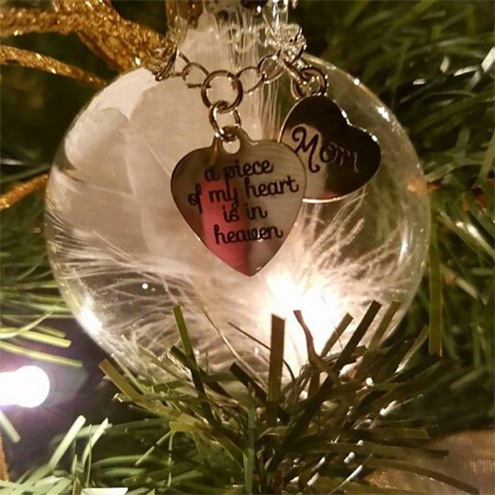 Elegant transparent julkula med vit fjäder och gravering, perfekt för juldekoration eller som en omtänksam gåva.