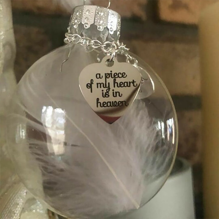 Elegant transparent julkula med vit fjäder och gravering, perfekt för juldekoration eller som en omtänksam gåva.