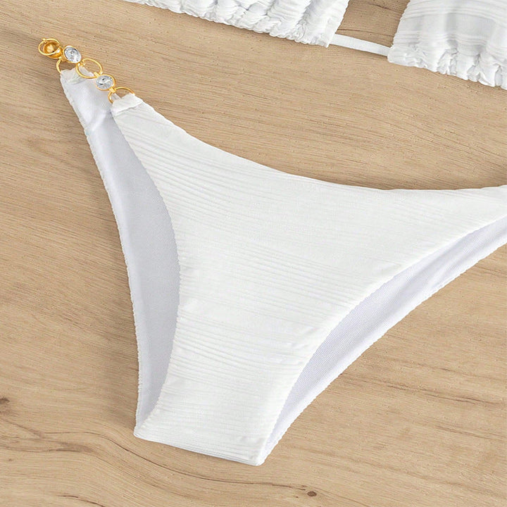 Fashionabel vit bikini med triangeltopp, smyckesdetalj och hög utskärning, sommarredo för stranden.
