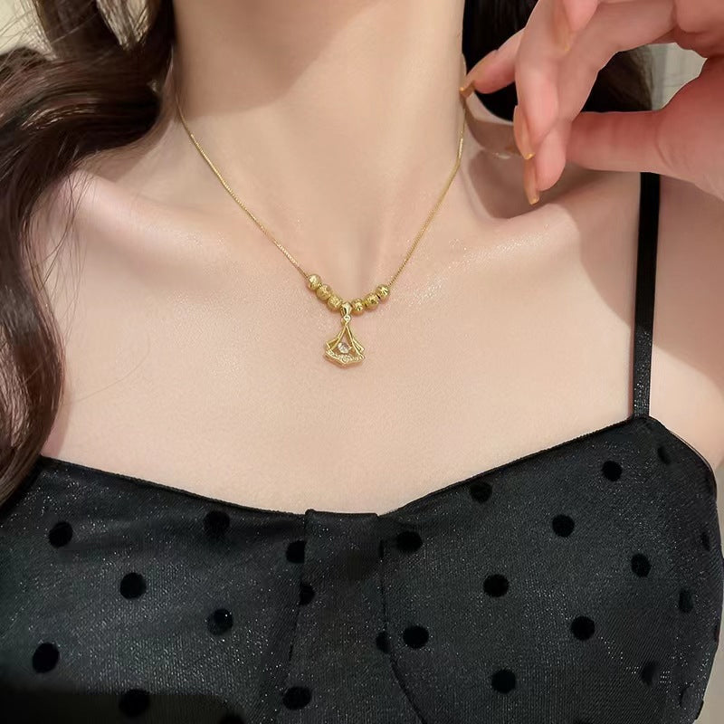 Närbild av ginkgo-lövshalsbandets detaljer med diamanter och guldplätering.