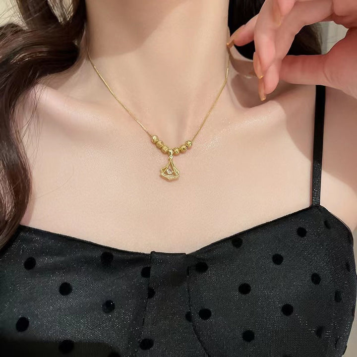 Närbild av ginkgo-lövshalsbandets detaljer med diamanter och guldplätering.