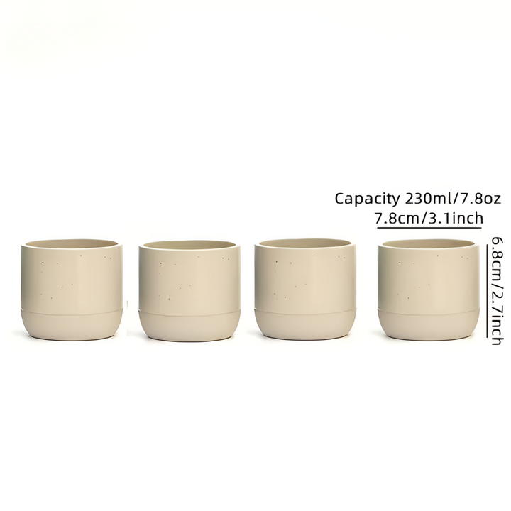 Elegant keramik kaffekopp bredvid en bok. 4-pack muggar för avkoppling. Ett fint muggset.