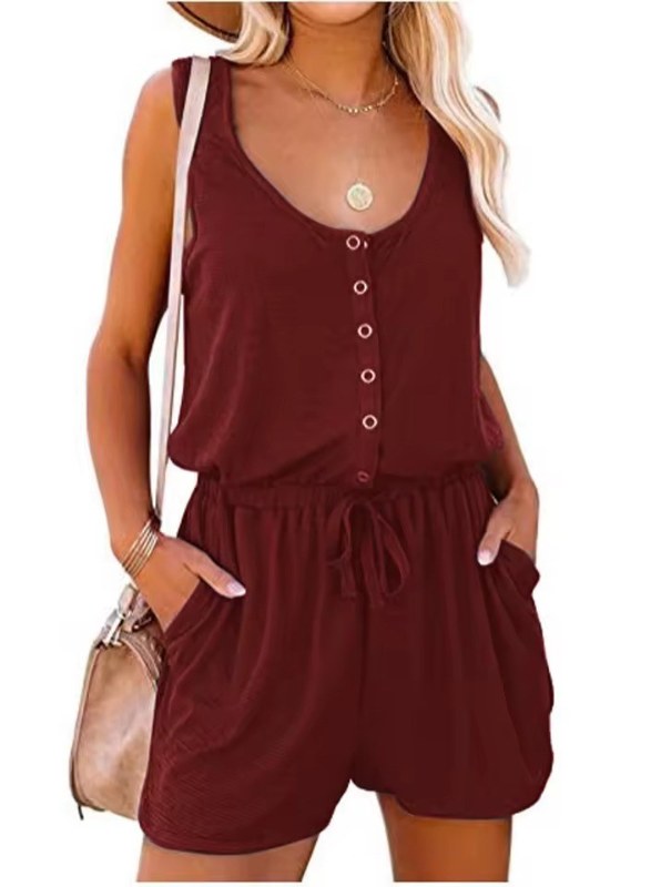 Modell visar en bekväm ärmlös kort jumpsuit med knappar, idealisk för soliga dagar och avslappnad stil.