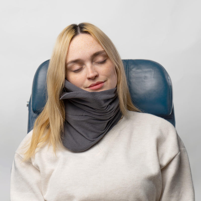 Person som sover i flygplanssäte med grå nackkudde