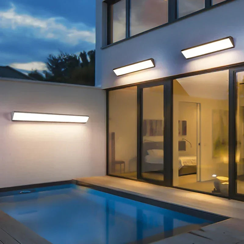 Stilrena LED-vägglampor för utomhusbruk installerade längs fasaden vid pool