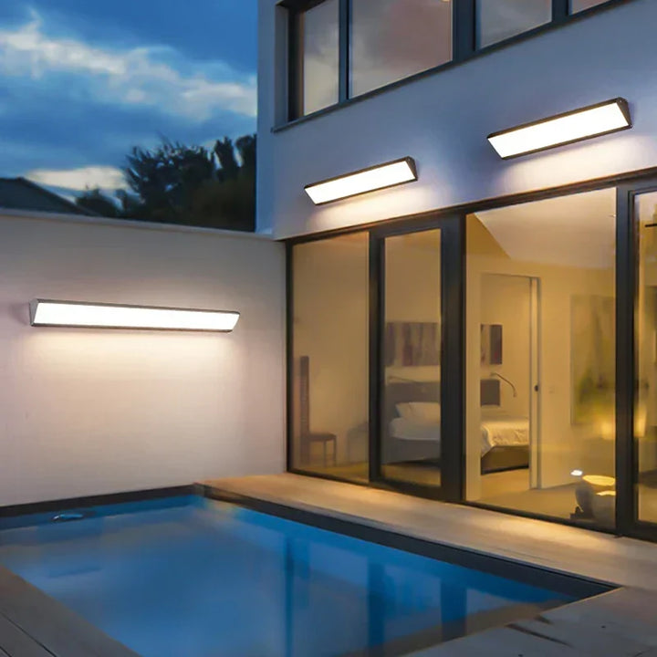 Stilrena LED-vägglampor för utomhusbruk installerade längs fasaden vid pool