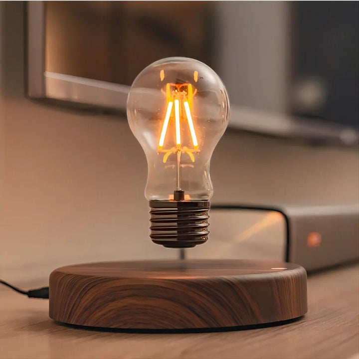 Magnetisk svävande LED-lampa med tänd glödlampa över träbas på skrivbord
