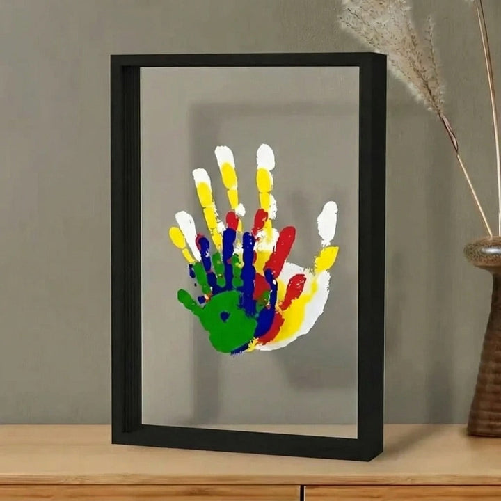 Svart ram med familjens handavtryck stående på en bänk
