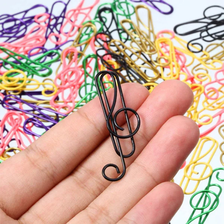 "Flerfärgade metallklämmor med musiksymboler, perfekta för att hålla musiknoter organiserade på skrivbordet."