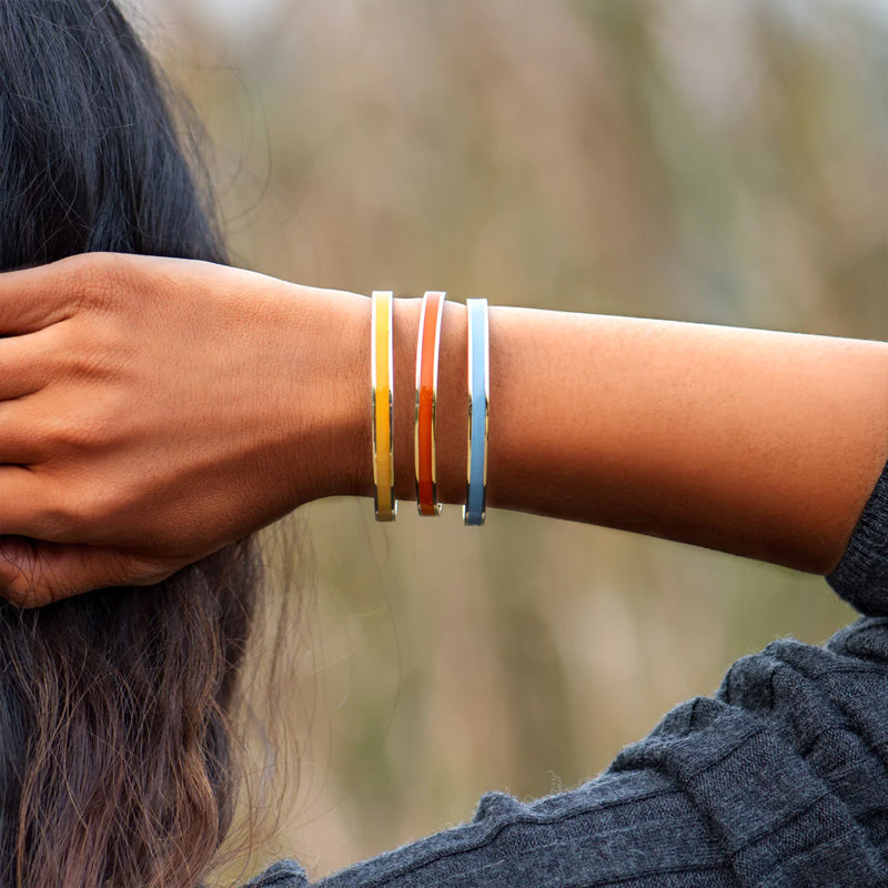 "Flerfärgat damarmband i robust stål med justerbar passform och livfulla orange, gula, blå, rosa, röda och svarta färger."