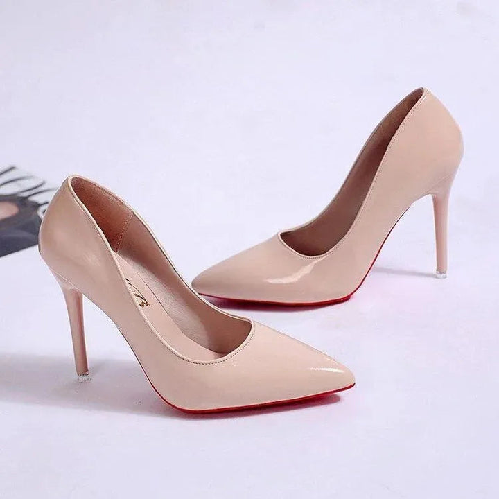 Två eleganta aprikosfärgade dam pumps med spetsig tå och smal klack på vit bakgrund