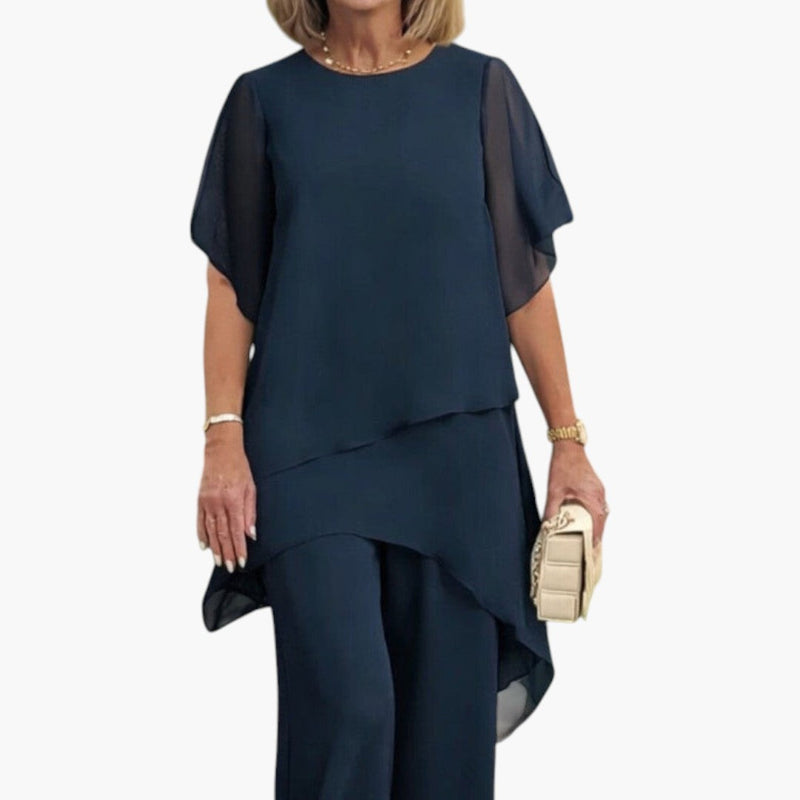 Närbild på den eleganta blå toppen med lagerdesign och vida byxor